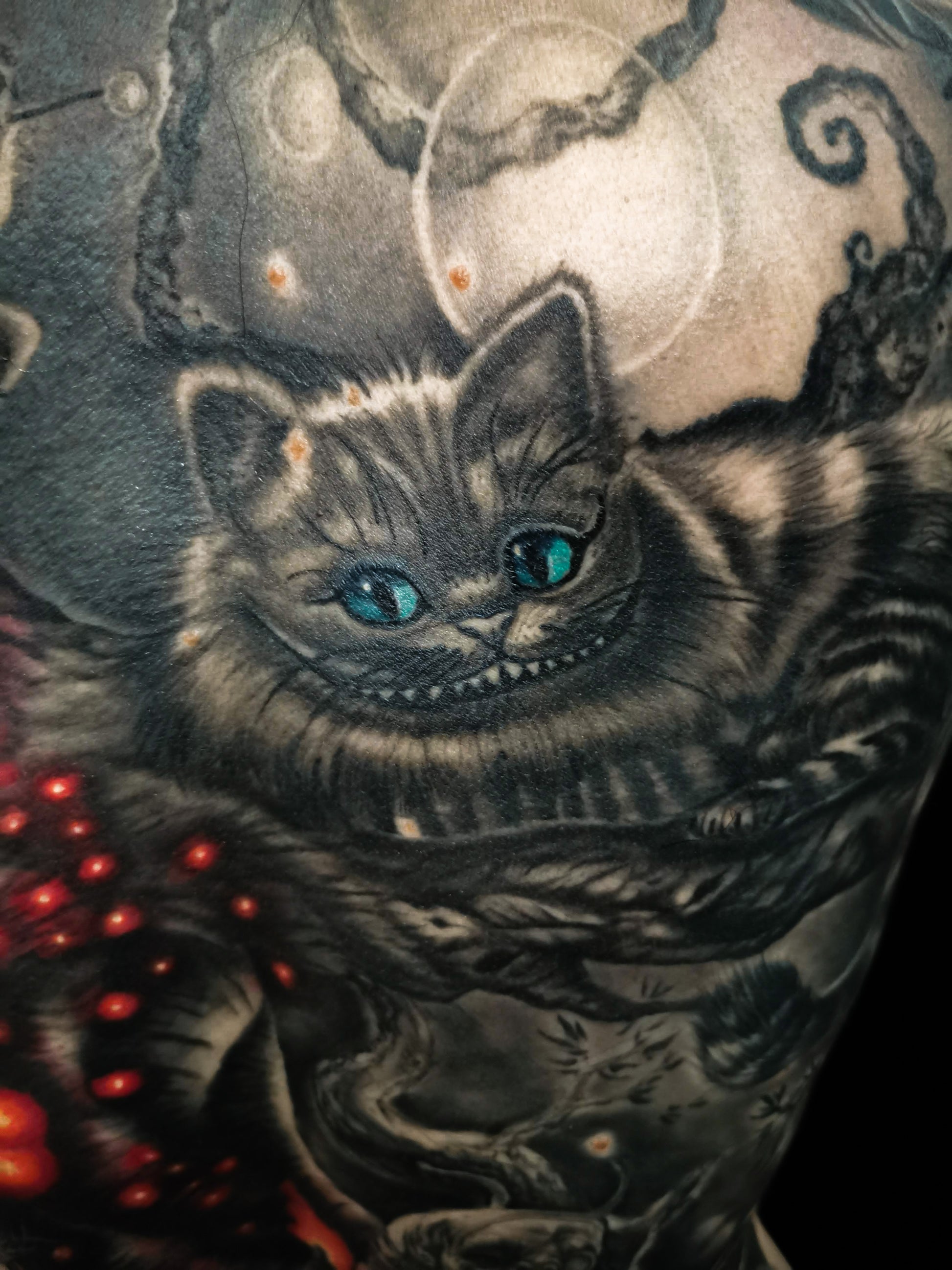 Detailed full back tattoo design of Alice in Wonderland with a cat, glowing eyes, and mystical elements