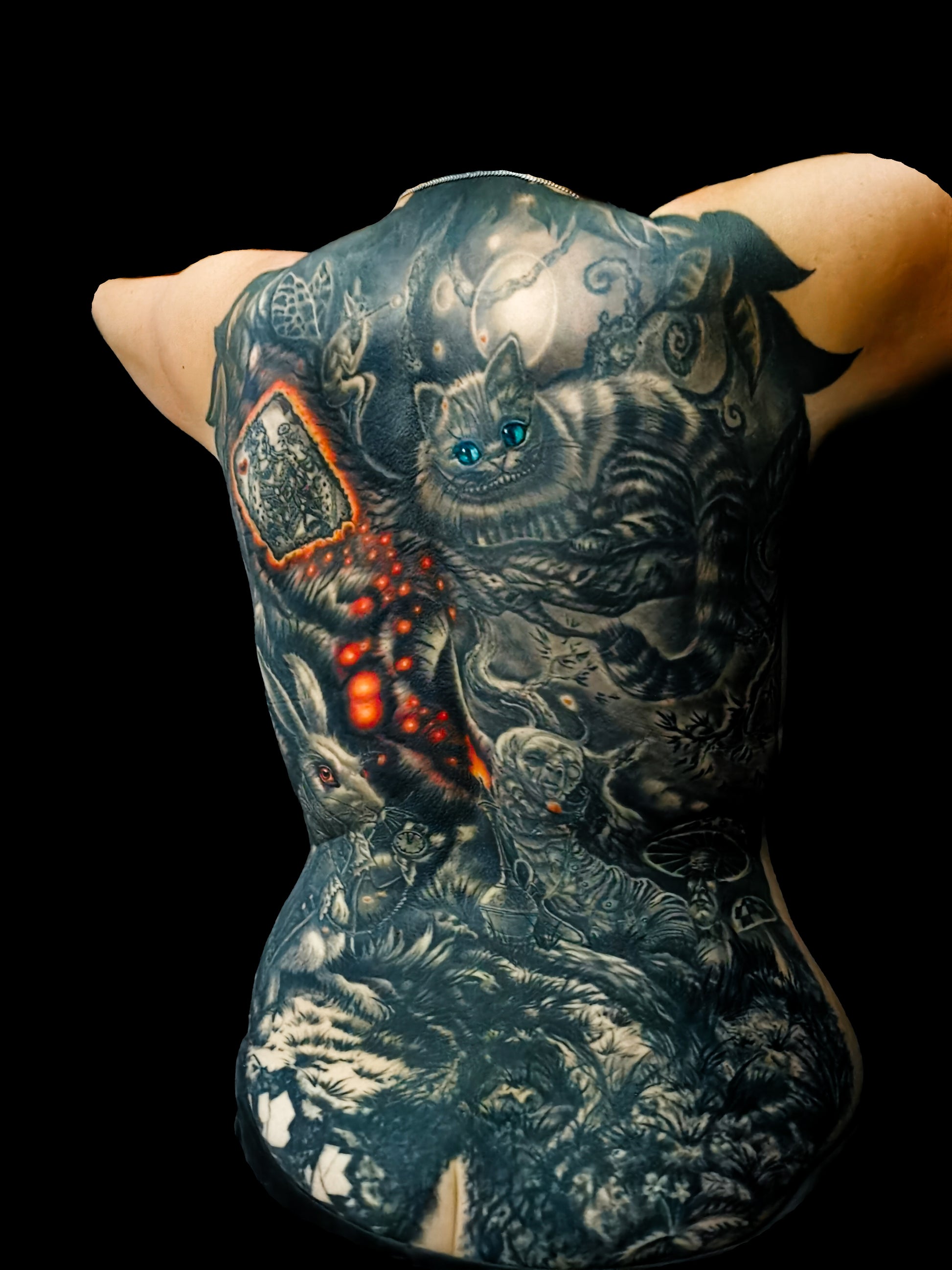 Detailed full back tattoo design of Alice in Wonderland with a rabbit, glowing eyes, and mystical elements
