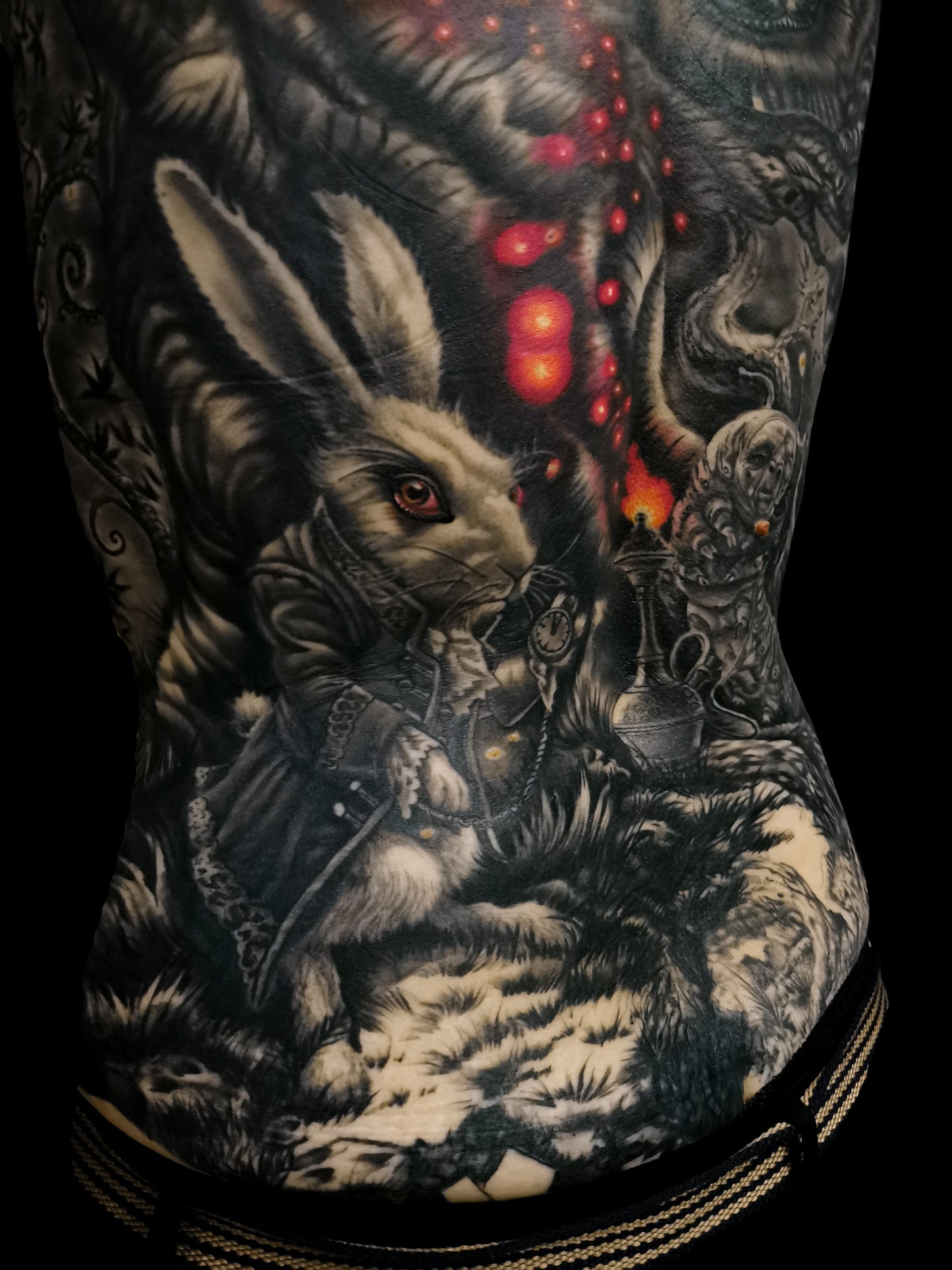 Detailed full back tattoo design of Alice in Wonderland with a rabbit, glowing eyes, and mystical elements