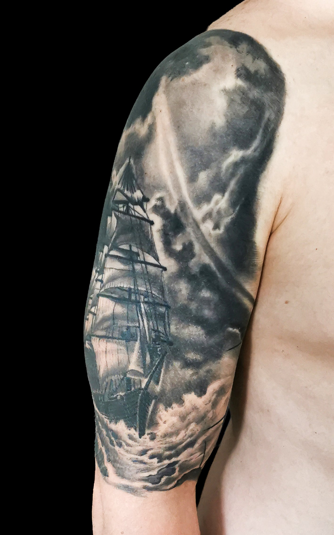 Halfsleeve tattoo on a person's right arm with anchor, compass, map and a ship in storm amongst waves and sunrays from the dark clouds
