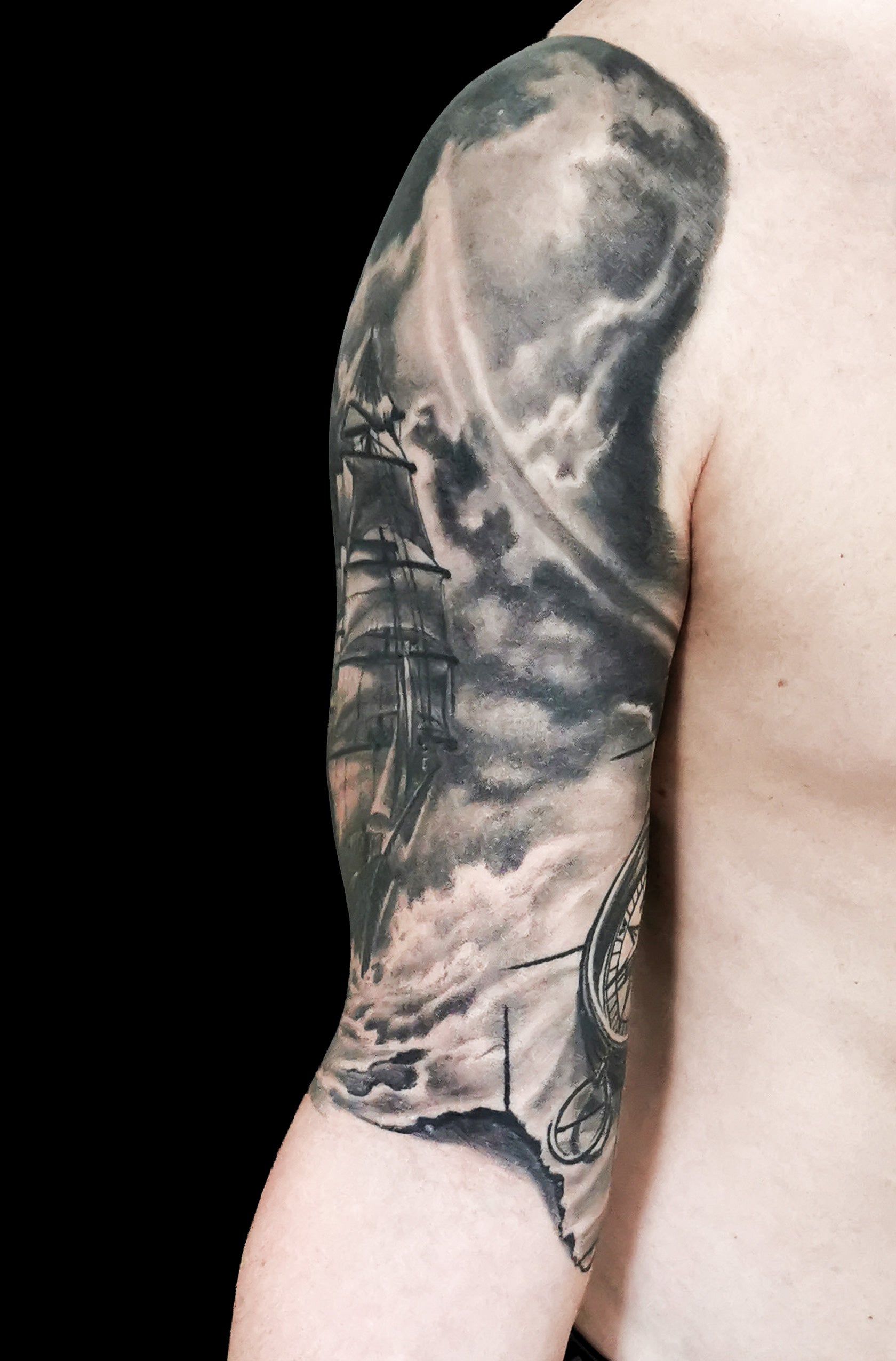 Halfsleeve tattoo on a person's right arm with anchor, compass, map and a ship in storm amongst waves and sunrays from the dark clouds