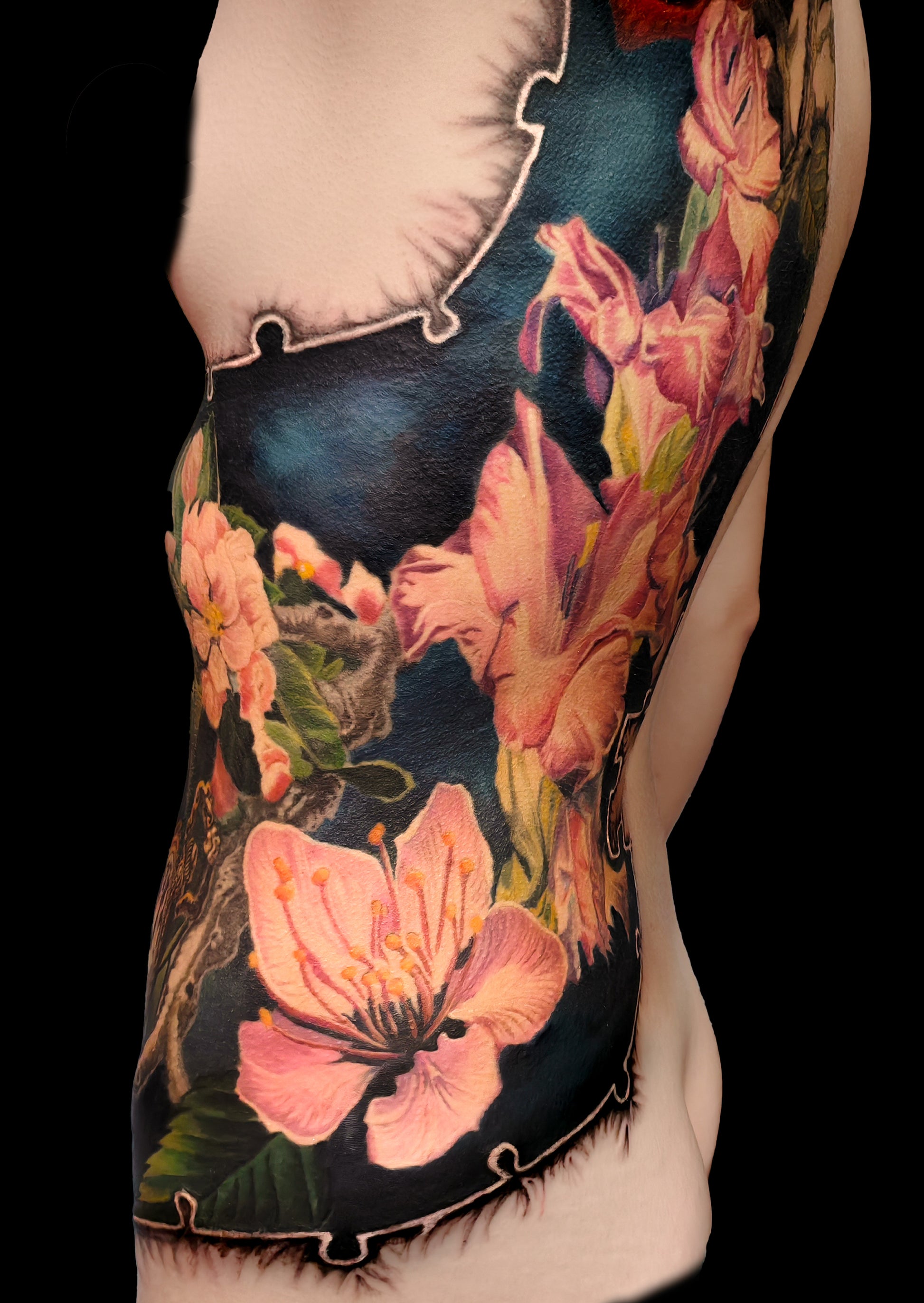 Colorful floral cover-up tattoo on the half torso with a puzzle-frame edge and a pocket watch motif